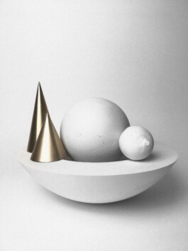 Abstract plaster bowl model containing two plaster spheres and two brass cones.