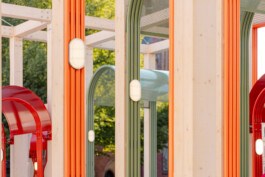 Detail of Dome Next Door, 2024, showing colourful arched steel elements, integrated lighting and the exposed timber structure of the urban art installation in Riga Old Town, Latvia.