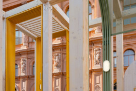 Detail of Dome Next Door, 2024, showing the timber structure and colourful framed elements against the historic architecture of Riga Old Town, Latvia.