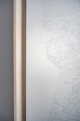 Detail view of The Paths of River, 2025, by Jurgis Gečys. Close-up of a hand drawing in pigment ink on paper showing delicate pale grey marks, dense point-like structures and flowing abstract forms beside the light wooden frame.